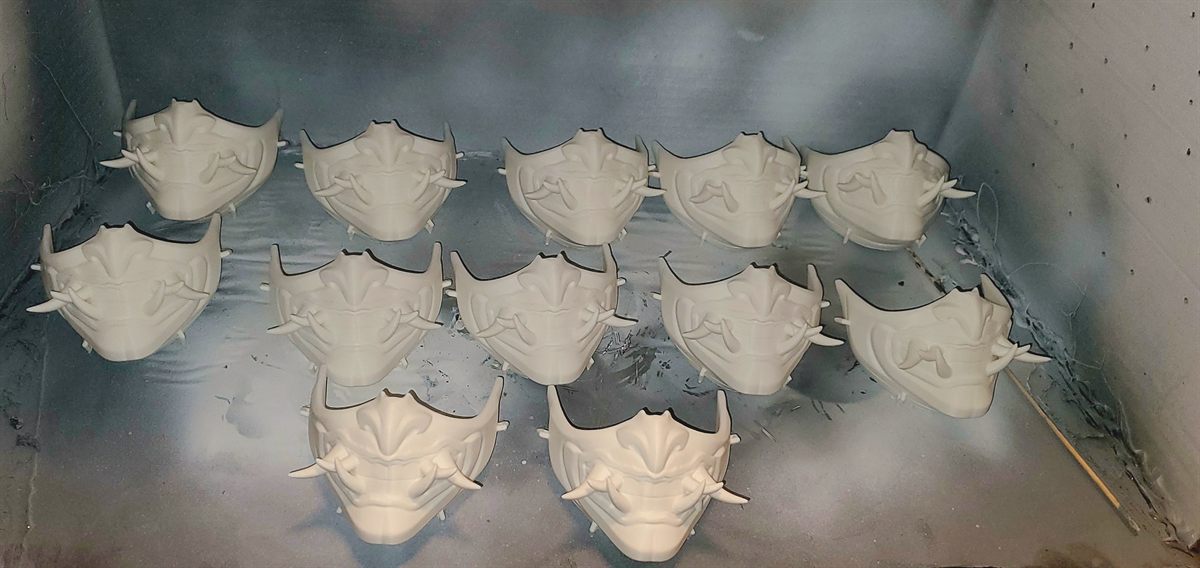 A batch of white 3D printed oni masks curing